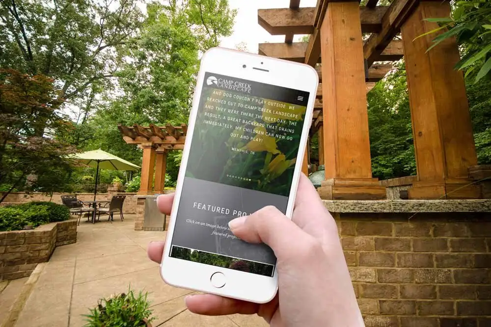 Camp Creek website on a phone in front of a pergola