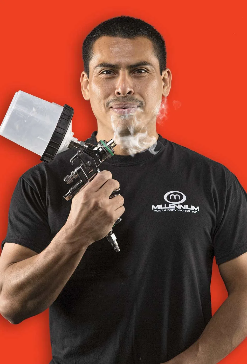 Millennium painter holding a spray gun with a wisp of smoke on a red background