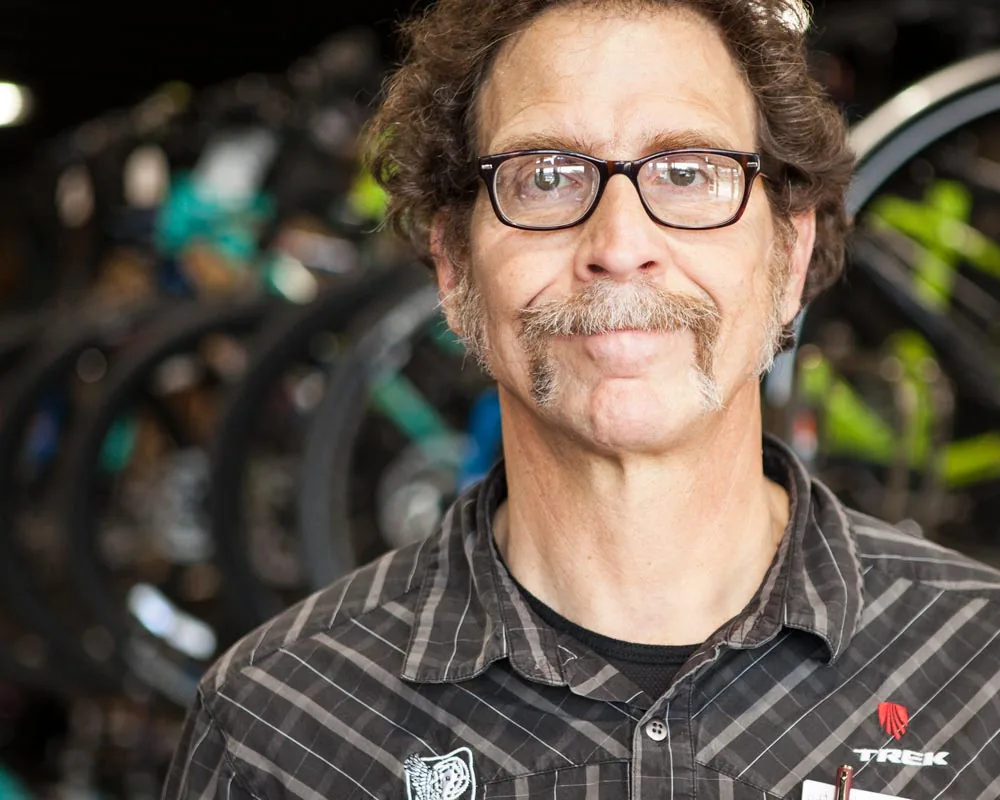 Peddler Bike Shop staff member smiling in front of a wall of bikes